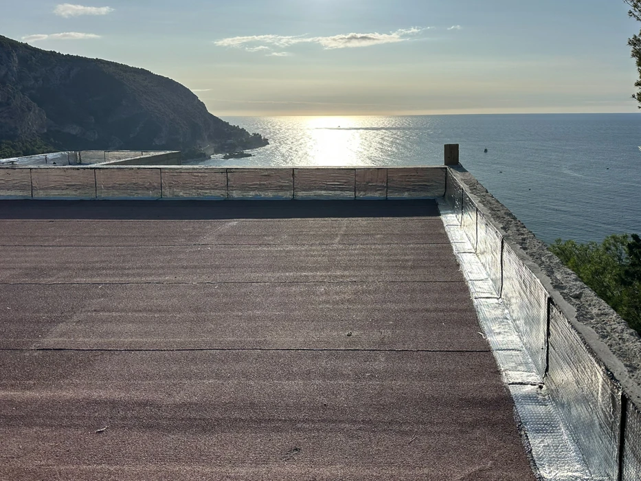 Terrasse en toiture avec étanchéité bitumineuse apparente, vue mer et montagne en arrière-plan au coucher du soleil