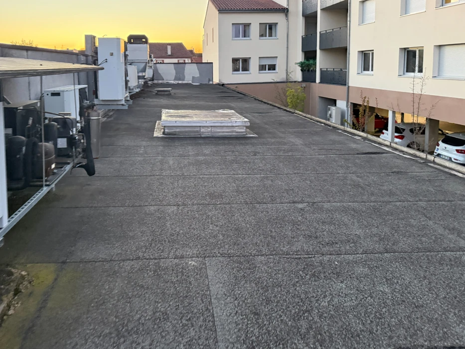 Toiture-terrasse plate vue en perspective, recouverte d'une membrane d'étanchéité bitumineuse de type SBS à finition granulée ardoisée