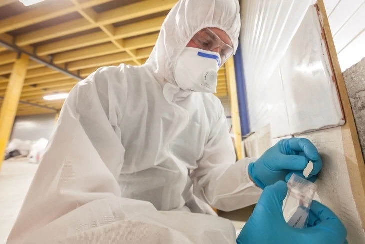 Scène extérieure de désamiantage avec technicien manipulant une plaque de fibrociment ondulé