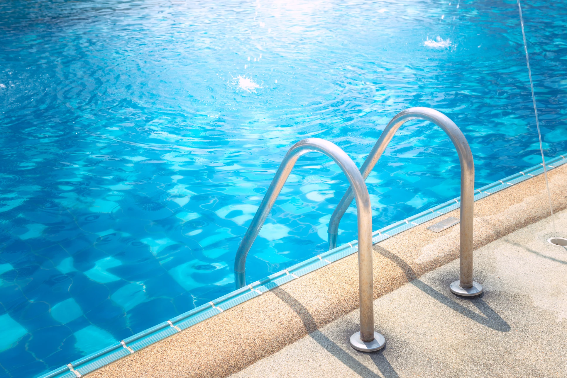 Ouvrier agenouillé sur plage de piscine en bois exotique, réalisant travaux de maintenance