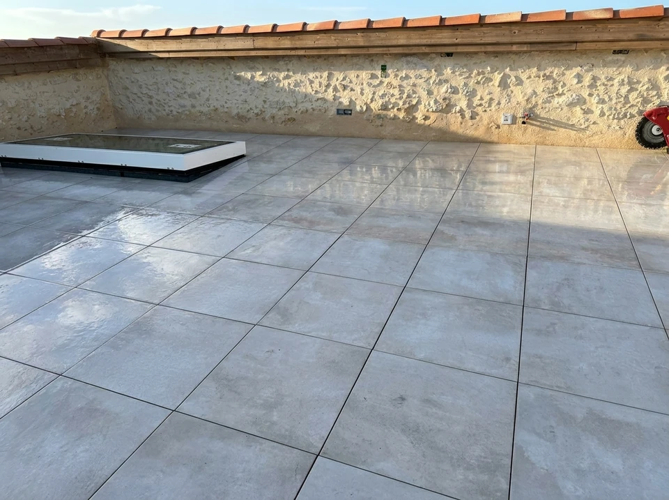 Chantier de construction extérieur avec ouvrier déroulant membrane d'étanchéité bitumineuse sur toiture-terrasse