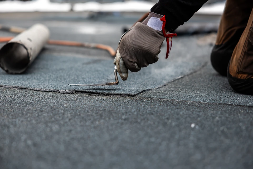 Chantier extérieur de revêtement de sol où un ouvrier applique un enduit de protection liquide bleu sur une surface bétonnée